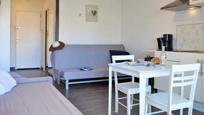 A compact living space with a bed, a sofa, a dining table with chairs, a kitchen area, and a small kitchenette.