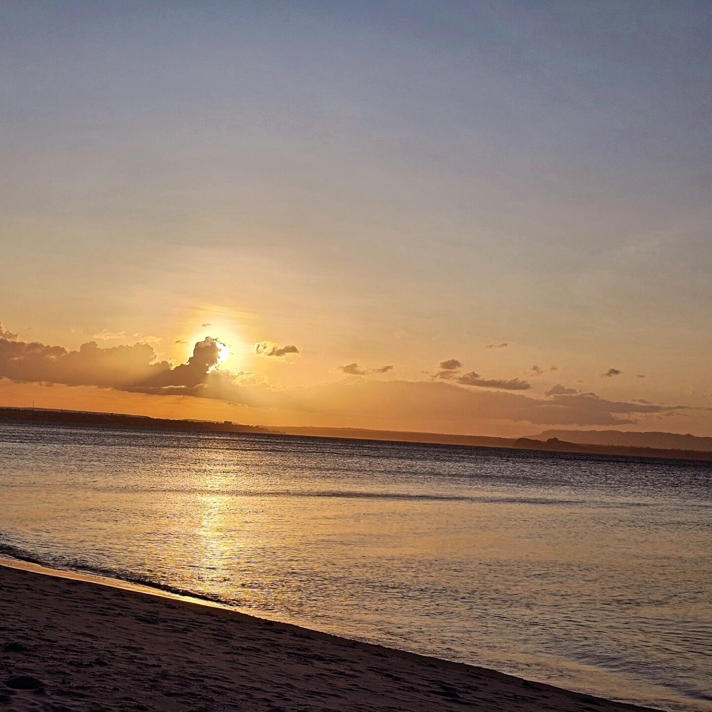 Una playa con un atardecer sobre el agua.