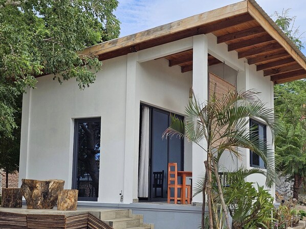 Una casa moderna con techo plano, ventanas grandes y un porche cubierto.