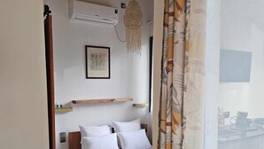 Un dormitorio con cama, aire acondicionado de pared, un cuadro enmarcado y una lámpara colgante.