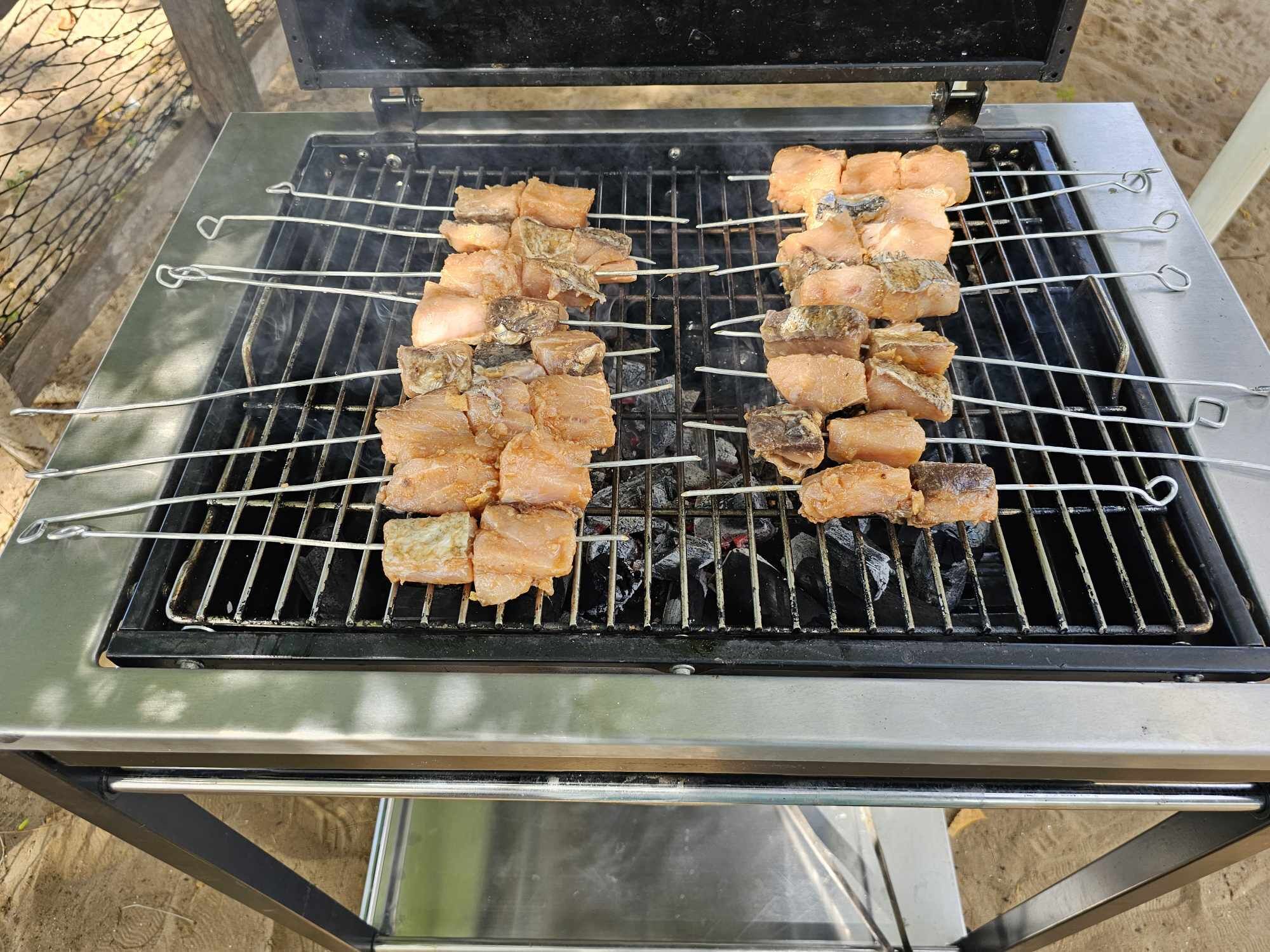 A portable grill with skewers of meat and vegetables.