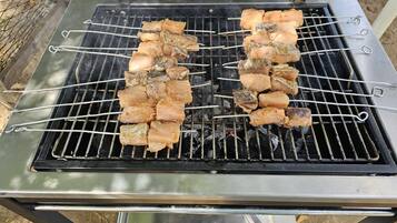 A portable grill with skewers of meat and vegetables.