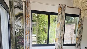 Una habitación con sofá, una mesita, una cesta tejida y una ventana con cortinas.