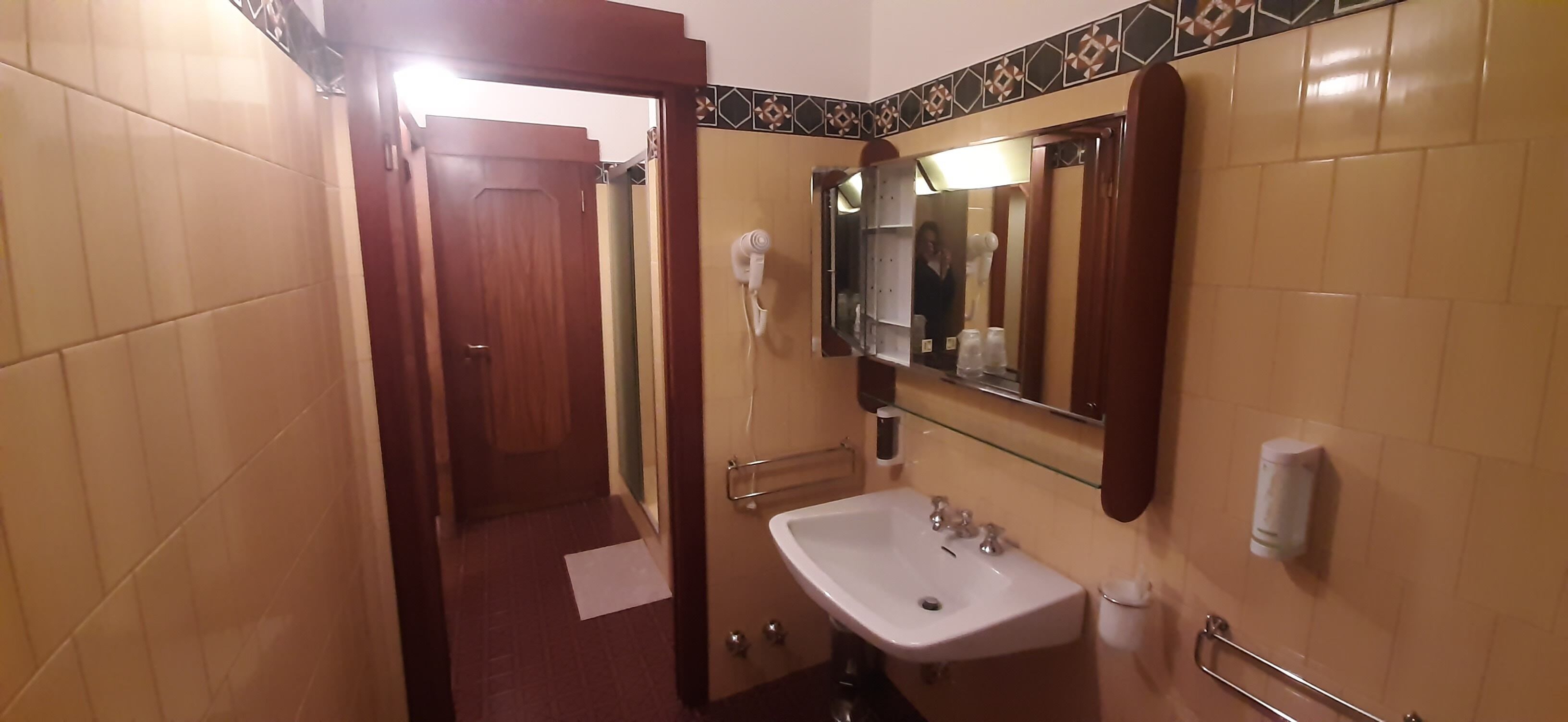 Ein Badezimmer mit Waschbecken, Spiegel, Handtuchhalter und Handtrockner.