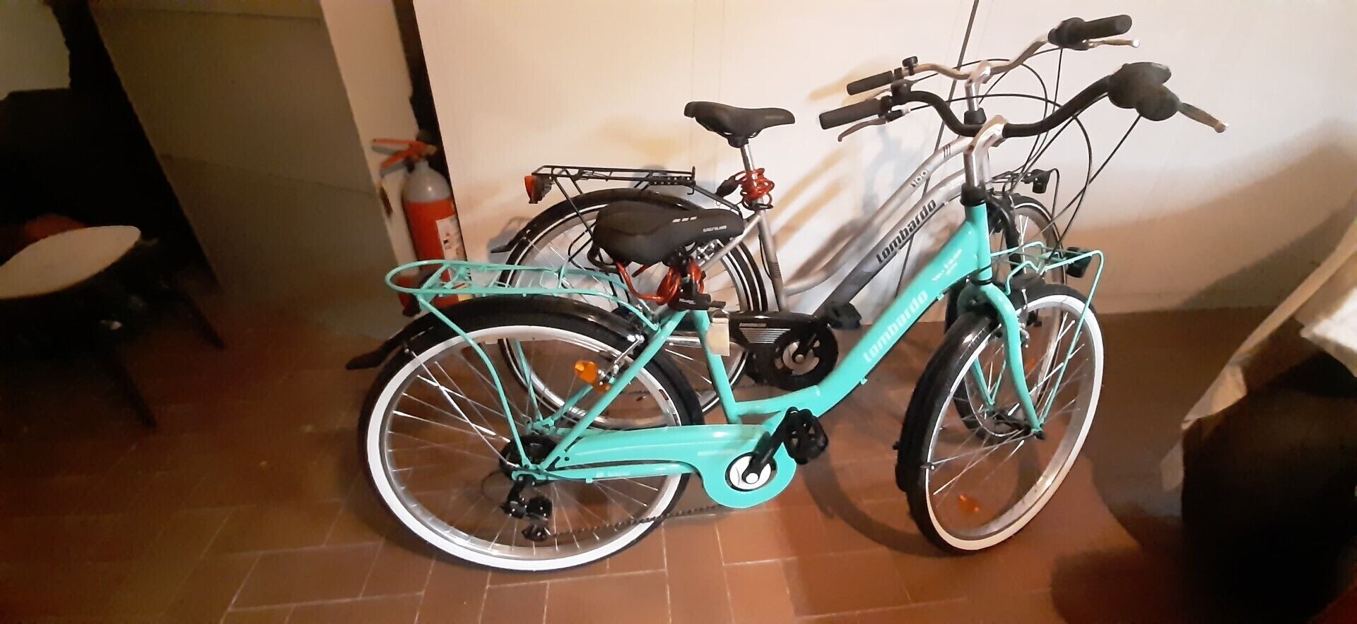 A teal bicycle with a basket and a water bottle, parked indoors.