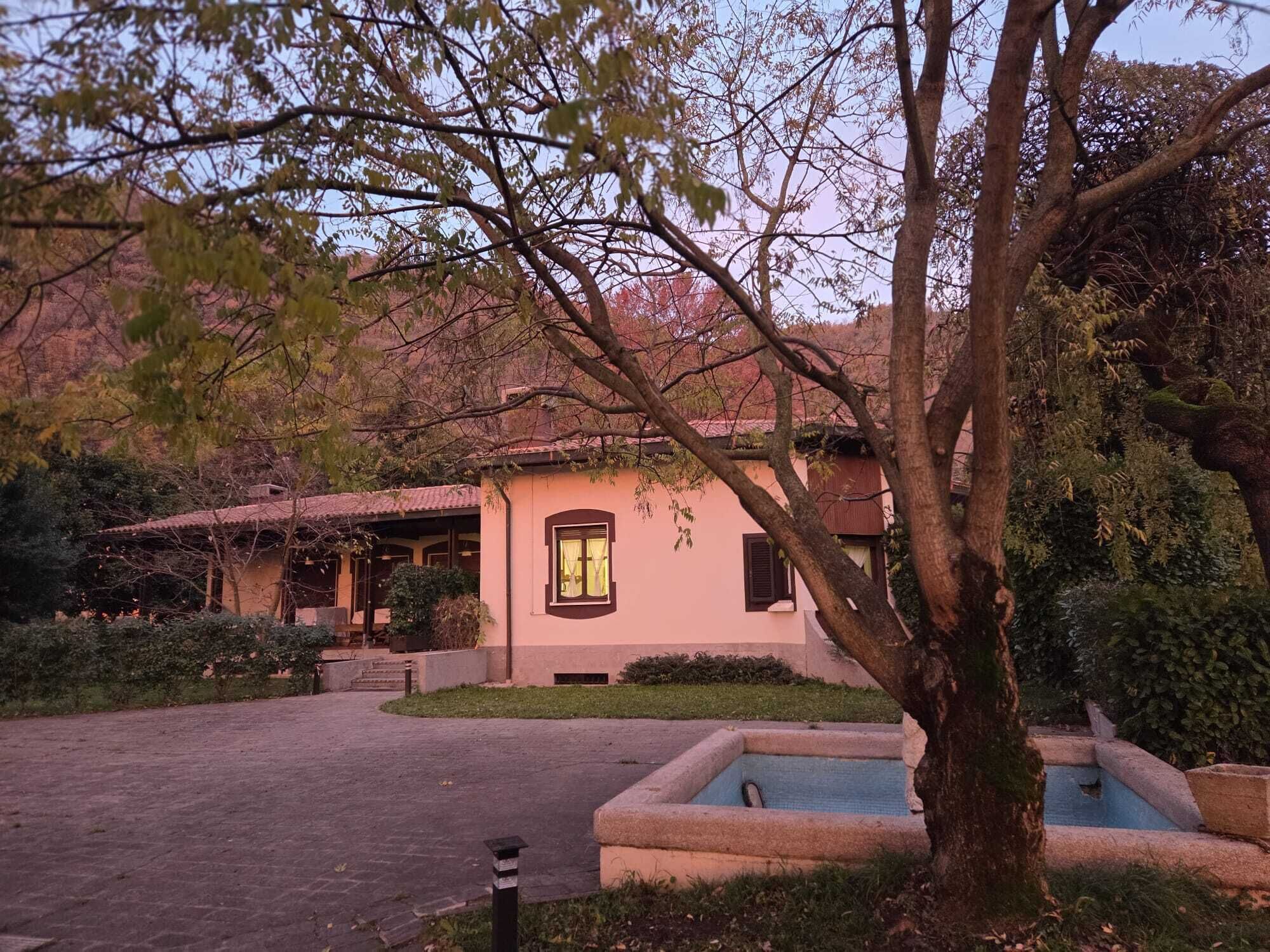A building with a tiled roof, a small window with curtains, and a paved courtyard with a fountain.