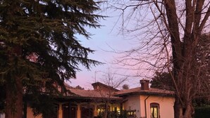 A traditional building with a tiled roof, surrounded by trees and a well-maintained lawn. - VILLA PARADIS B&B (Airuno)