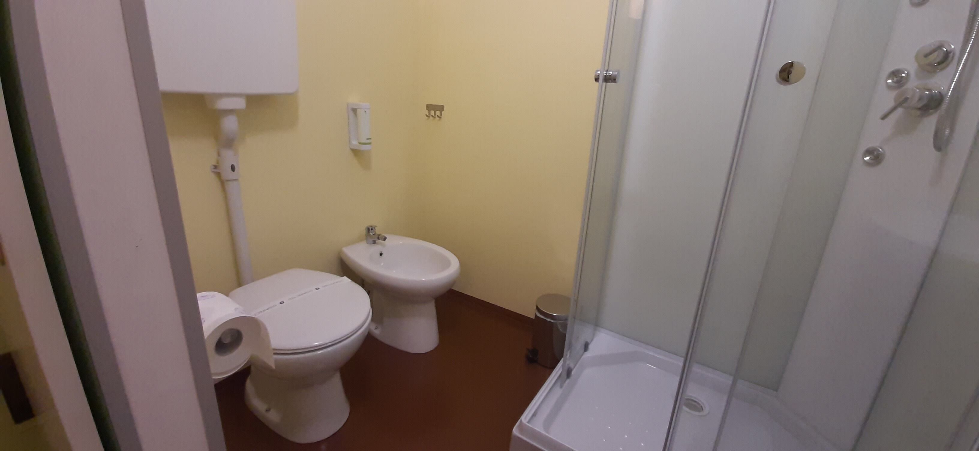 Un baño con inodoro, bidé y cabina de ducha con paredes de vidrio.