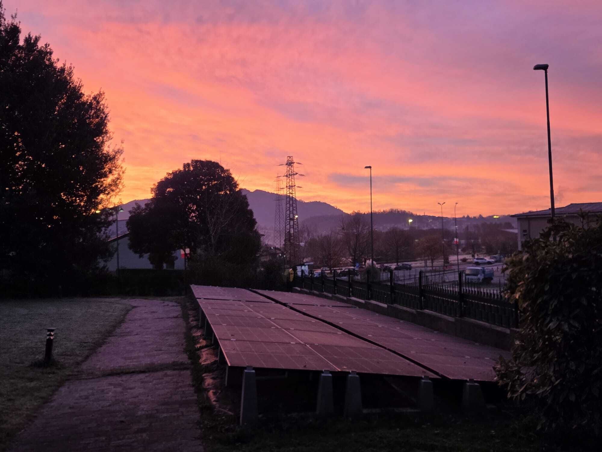A sunset view with a park area, benches, and distant buildings.
