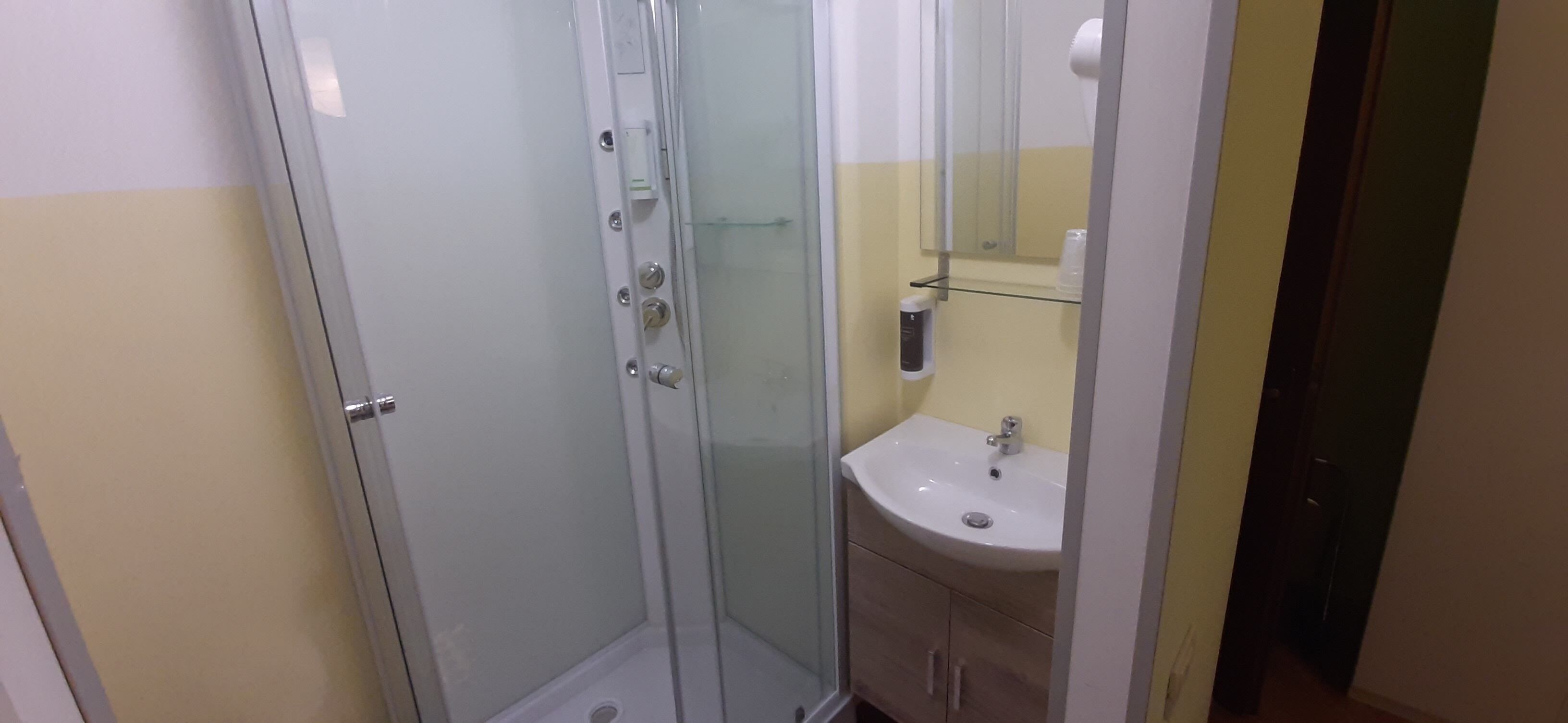 Un baño con ducha de vidrio, lavamanos y espejo.