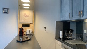 A modern kitchen with a wooden accent wall, a coffee machine, a toaster, and a dishwasher. - Renovated studio in Pra Loup with balcony and wifi, close to cable car (Pra-Loup)