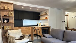 A modern living room with a grey sofa, wooden coffee table, and a fluffy chair. - Cosy Duplex, 3 Bedrooms + Bunk Area, Near Slopes, Garage, Ski Locker, No Smoking (Les Gets)