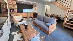 A modern living space with a kitchen, dining area, and a wooden staircase. - Cosy Duplex, 3 Bedrooms + Bunk Area, Near Slopes, Garage, Ski Locker, No Smoking (Les Gets)