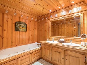 Relax in a spacious bathroom with a bathtub, two sinks, and a framed picture of a canoe.
