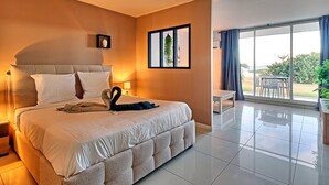 A spacious bedroom with a large bed, a small table, and a balcony with a view. - Romantic Getaway Near Orient Bay Beach (Saint-Martin)