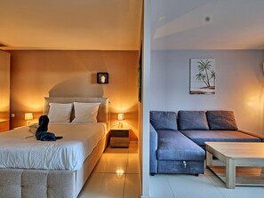 A hotel room with a bed, bedside tables, a sofa, and a coffee table.