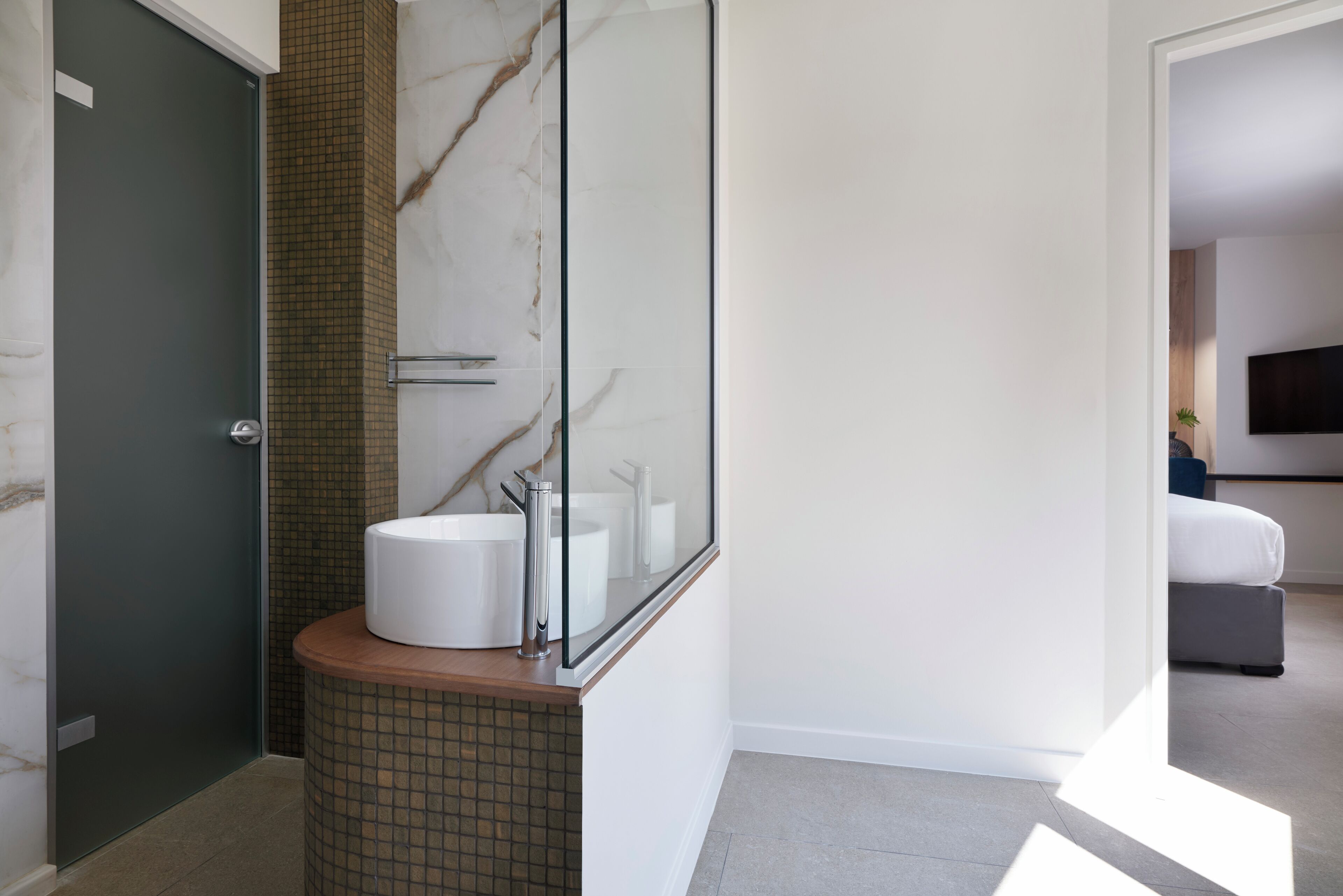 A modern bathroom with a marble wall, a sink, and a glass shower enclosure.