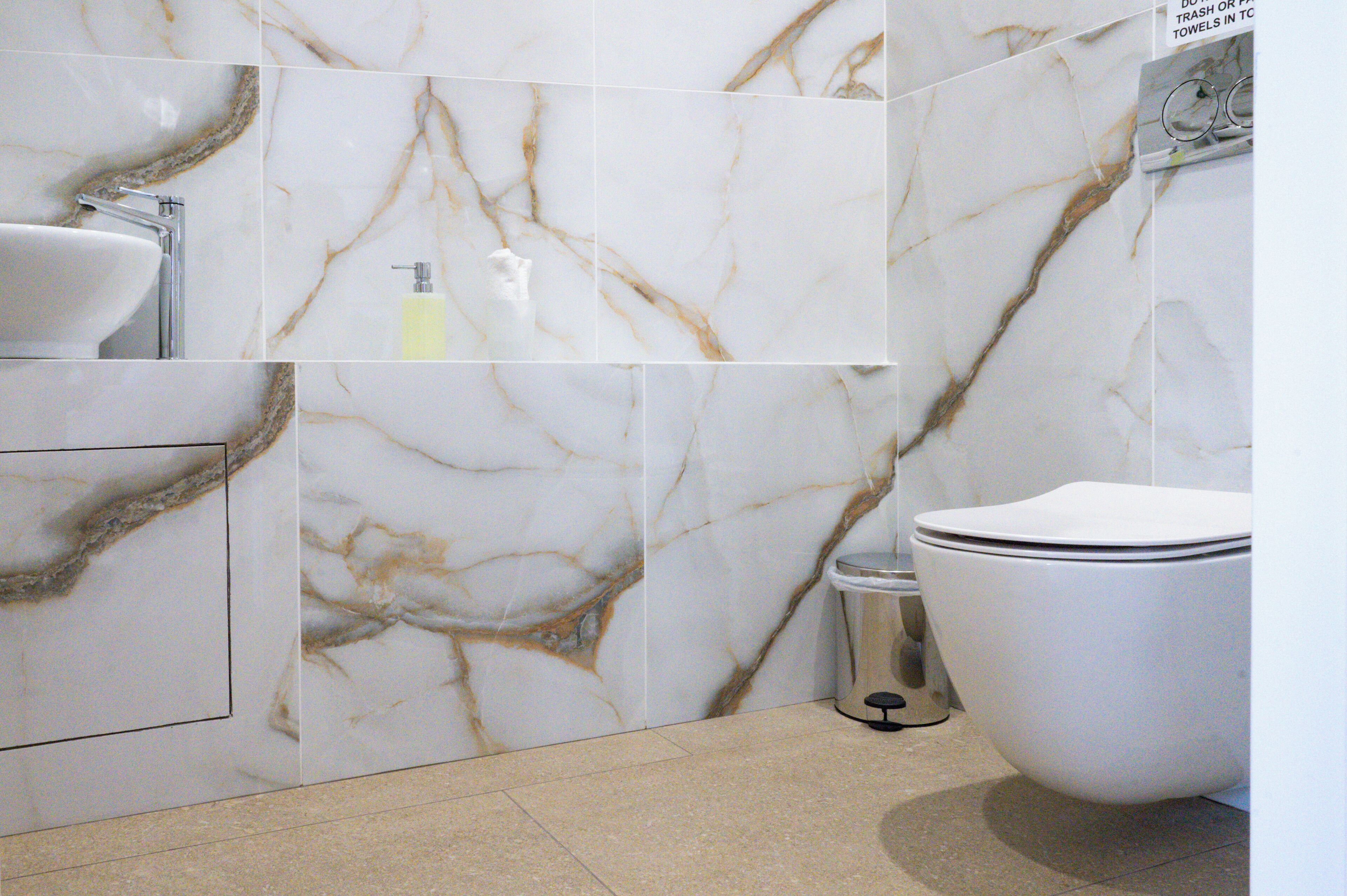 Une salle de bain avec un mur en marbre, un lavabo et des toilettes.
