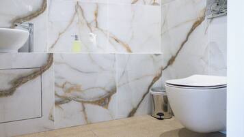 Une salle de bain avec un mur en marbre, un lavabo et des toilettes.