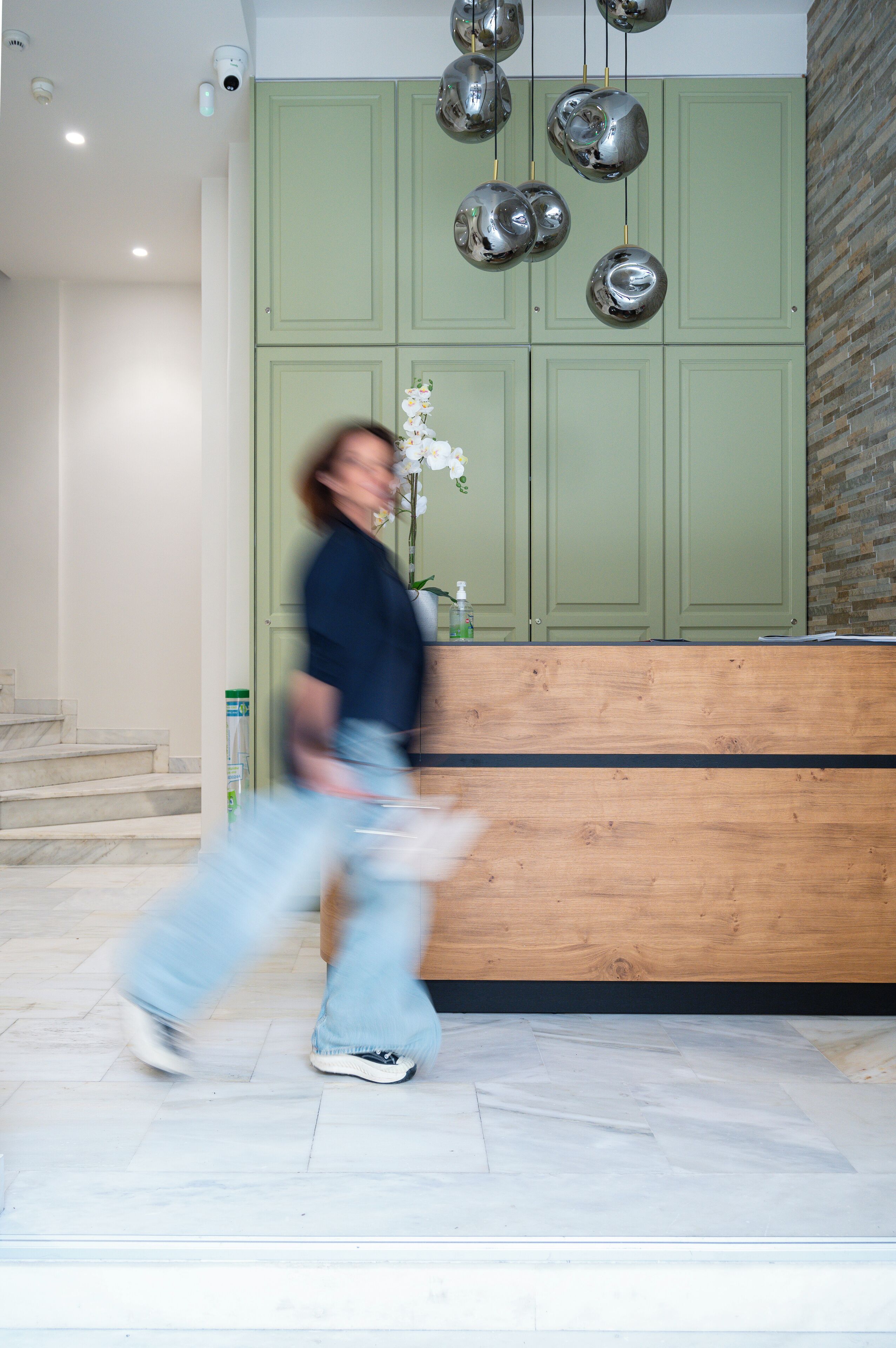 A reception area with a green wall, a wooden reception desk, and a marble floor.