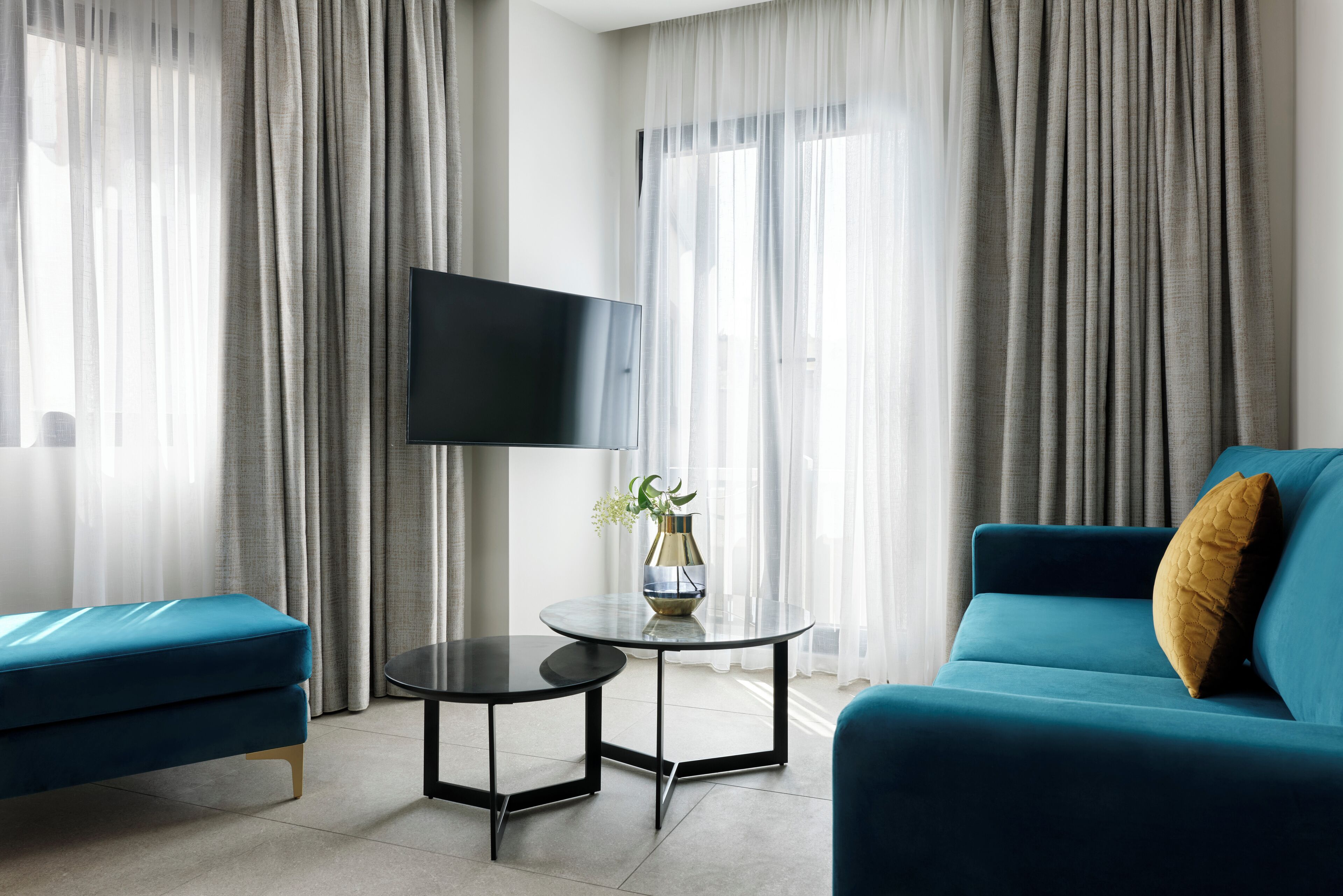 Ein modernes Wohnzimmer mit einem blauen Sofa, einem kleinen runden Tisch und einem flachbildfernseher an der Wand.