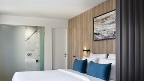 A modern hotel room with a large bed, a wooden panel wall, and a painting above the bed. - Hestia - Kolokotroni 23 (Athens)