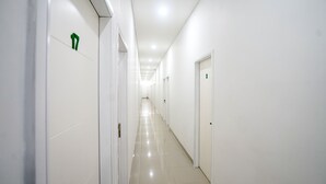 En lång, smal hall med vita väggar och dörrar, som leder till flera rum.