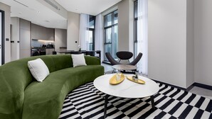 A modern living room with a green sofa, a round coffee table, and a checkered floor.