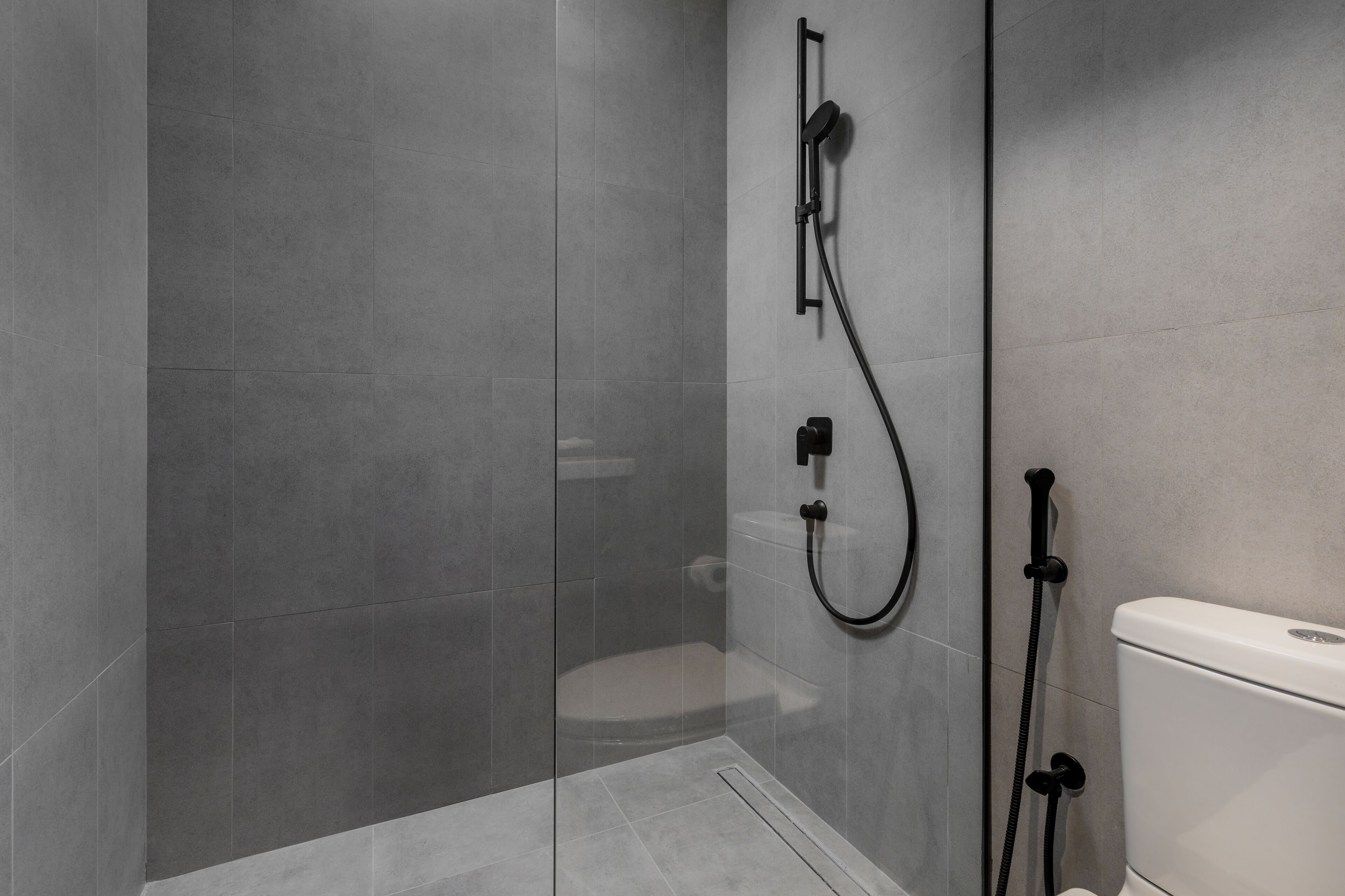 A modern bathroom with a glass-enclosed shower, a toilet, and a sink.