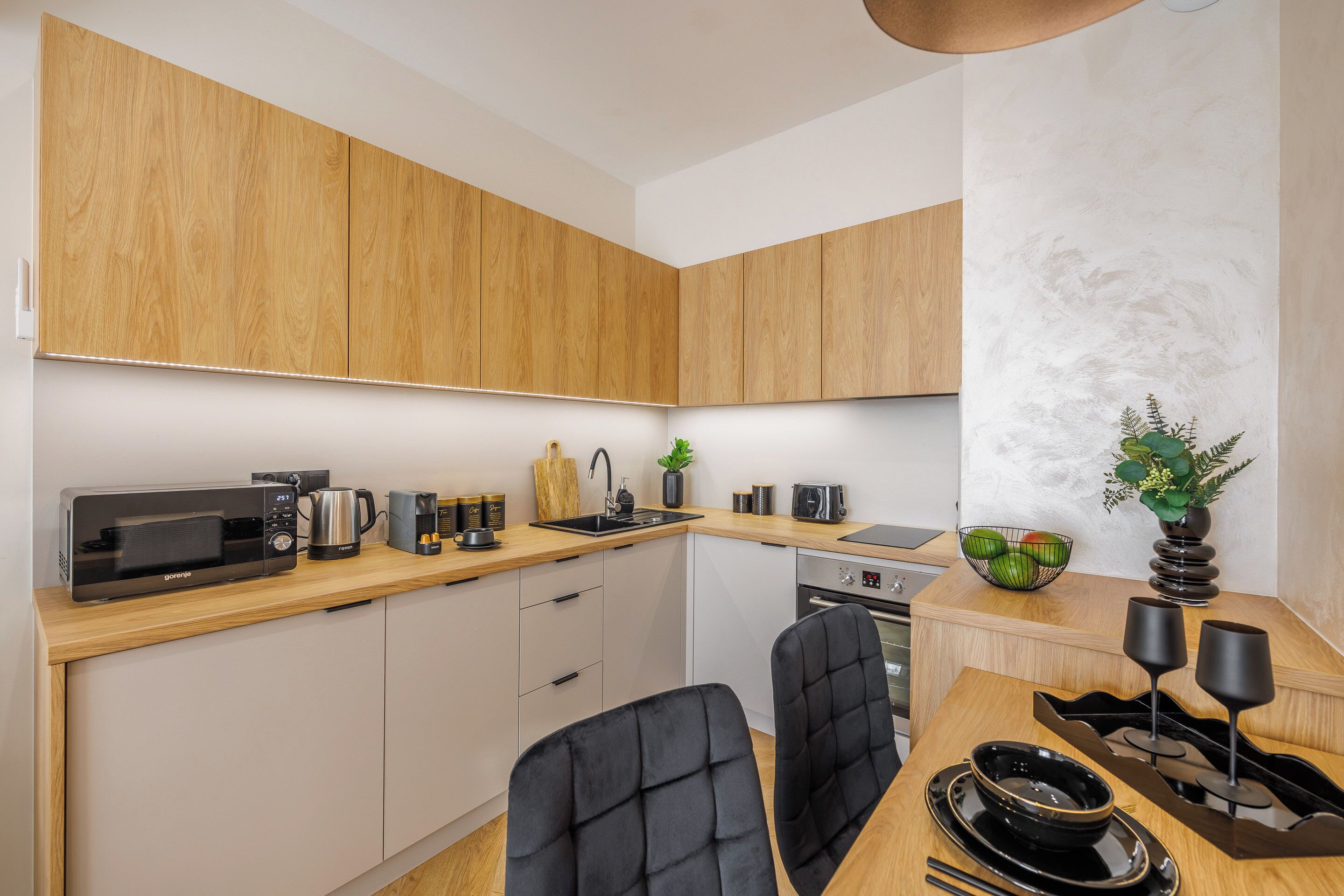 A modern kitchen with wooden cabinets, a microwave, coffee maker, and a sink.