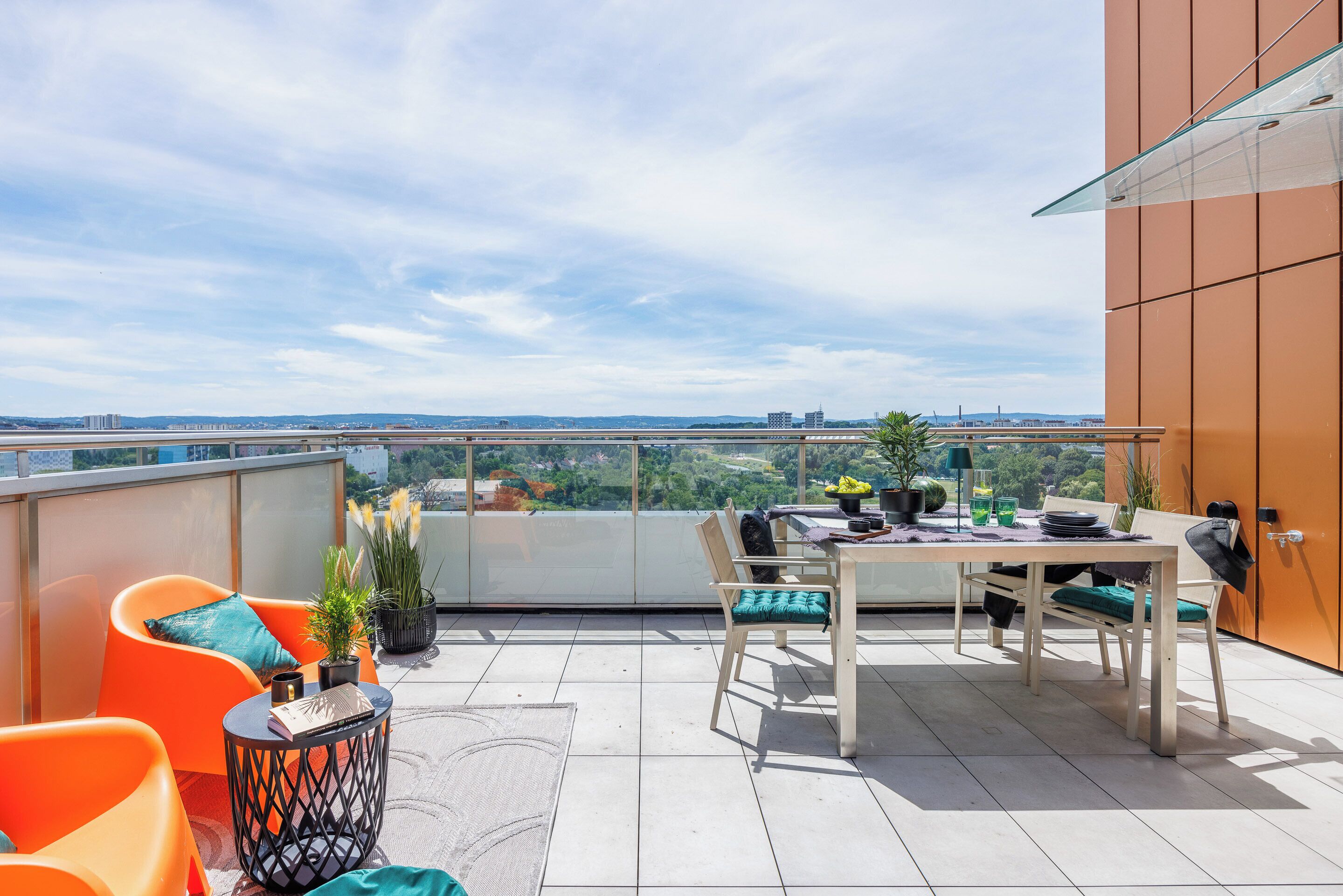 A rooftop terrace with a table, chairs, and potted plants.