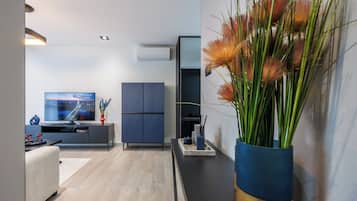 A modern living room with a flat-screen TV, a dark blue cabinet, and a decorative plant.