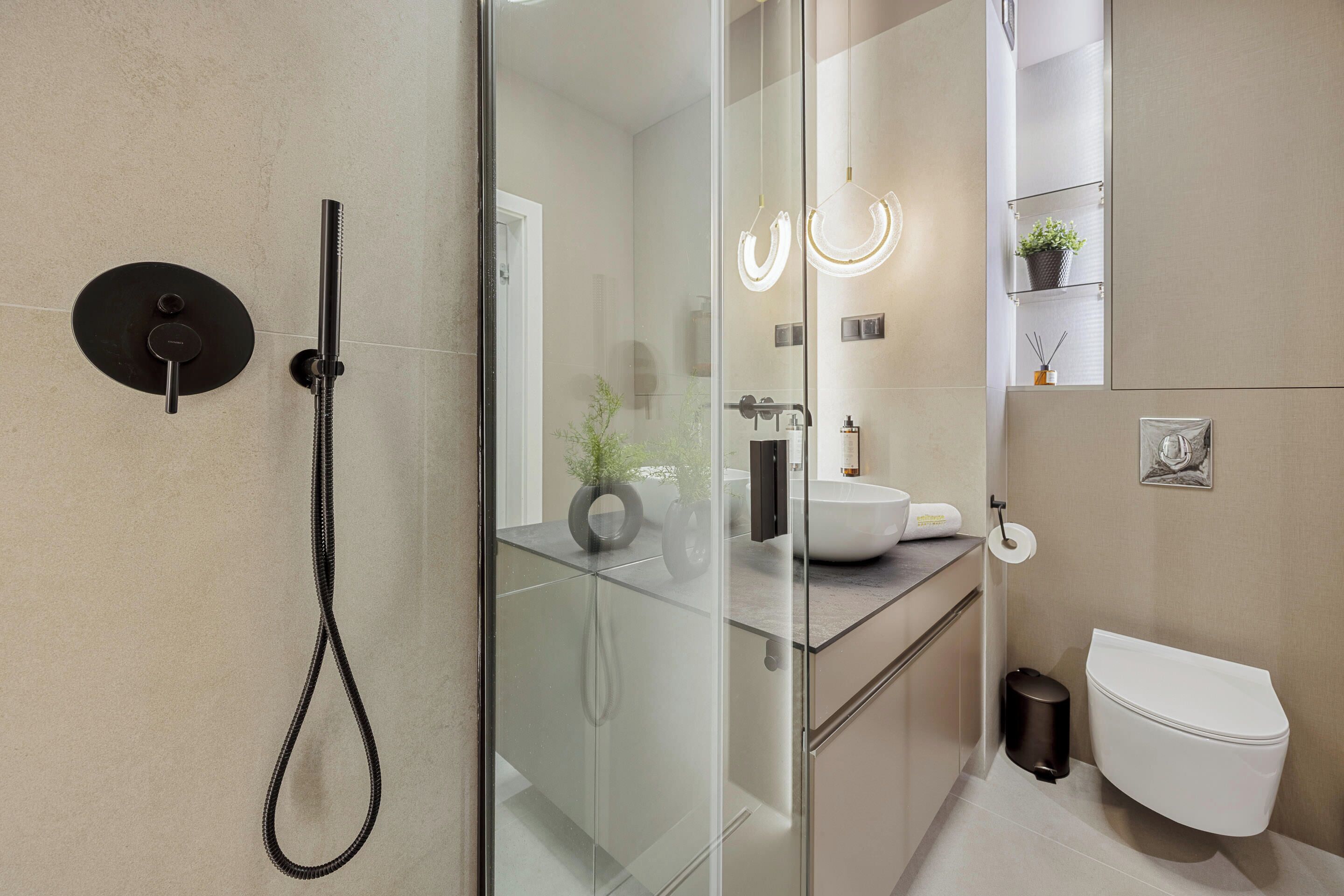 A modern bathroom with a glass shower enclosure, a white toilet, and a sink with a mirror above it.