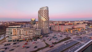 Un hotel moderno con fachada curva, varios pisos y un estacionamiento con varios coches.