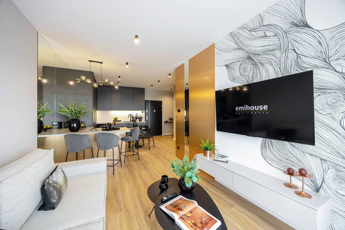A modern living room with a sofa, coffee table, and a flat-screen TV mounted on the wall.