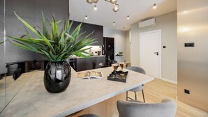 Una cocina moderna con una isla grande, una planta en maceta y un comedor con sillas.