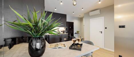 Una cocina moderna con una isla grande, una planta en maceta y un comedor con sillas.