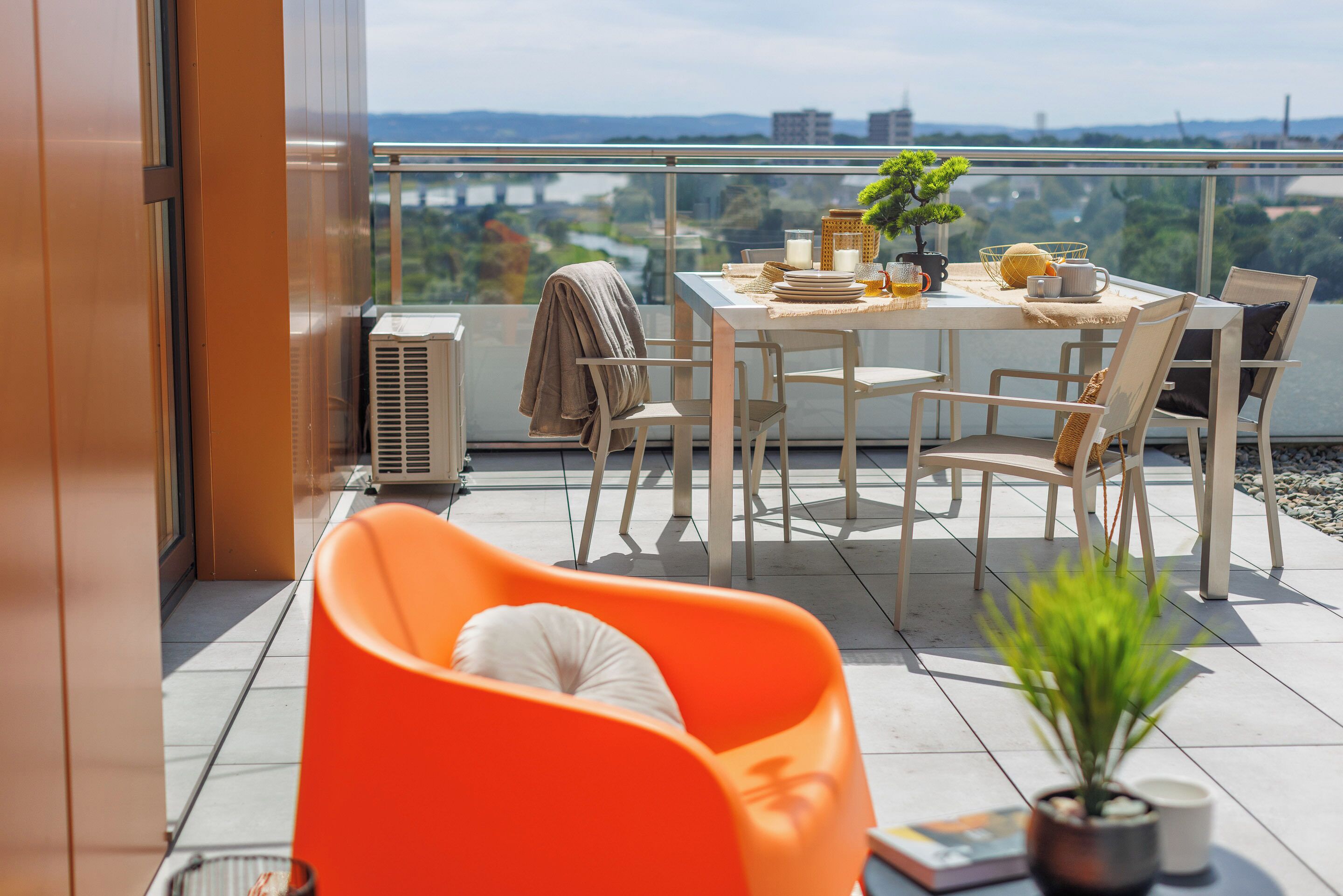 A balcony with a dining table, chairs, and a potted plant.