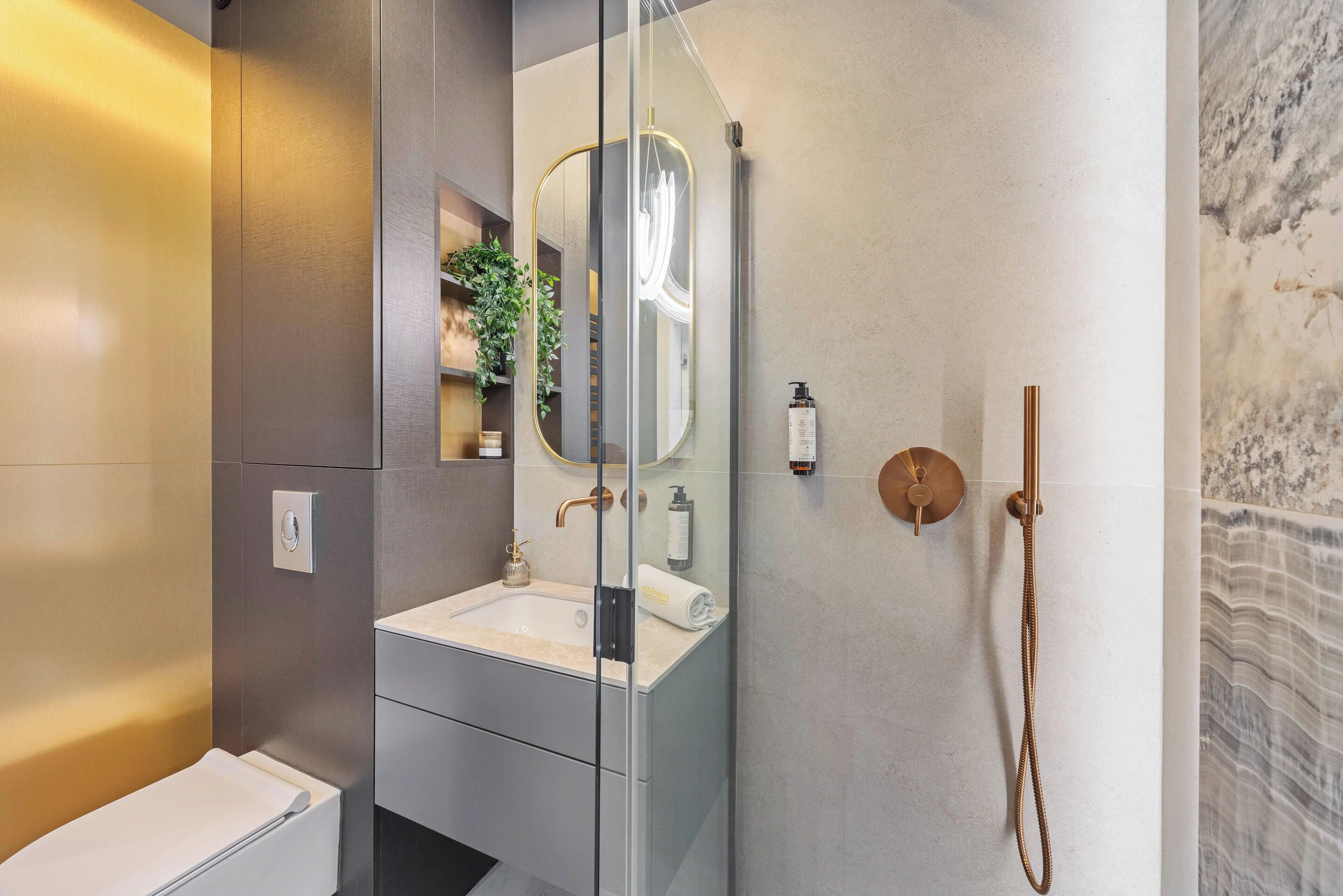 A modern bathroom with a glass shower enclosure, a sink with a mirror, and a towel rack.