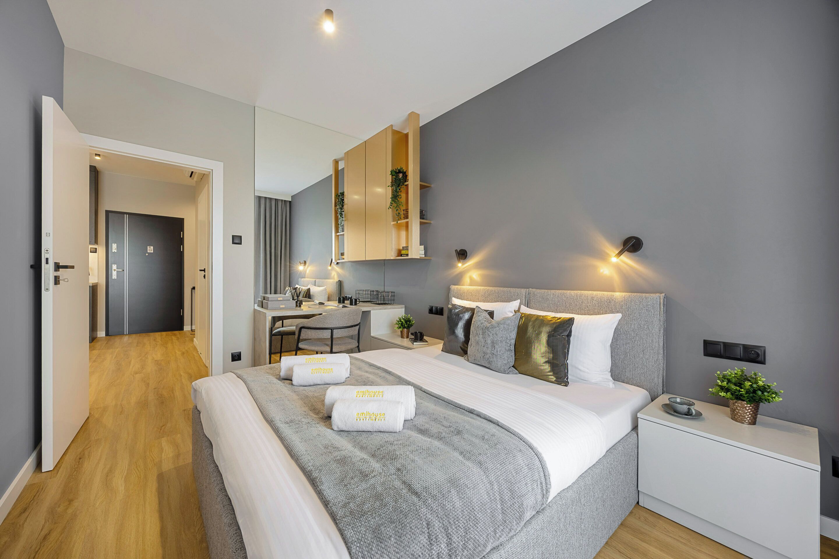Una habitación de hotel moderna con una cama grande, mesitas de noche, un escritorio y un espejo.