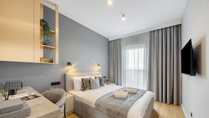 Una habitación de hotel moderna con una cama grande, mesitas de noche, un escritorio y un televisor montado en la pared.