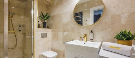Een moderne badkamer met een douche met glazen wand, een toilet, een wastafel met spiegel en een handdoek met de tekst 'enjoyse'.