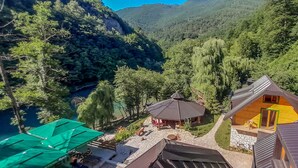 A mountain lodge with multiple cabins, a stone pathway, and a view of a forested valley. - Rafting Camp Encijan (Foca)