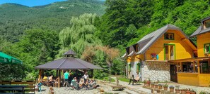 A wooden cabin with a stone foundation, a gazebo, and a patio area with seating. - Rafting Camp Encijan (Foca)