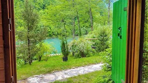 A view through a green door of a lush garden with a stone path leading to a body of water. - Rafting Camp Encijan (Foca)