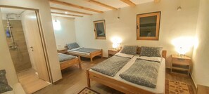 A bedroom with two single beds, a wooden floor, a shower area, and a window with a wooden frame. - Rafting Camp Encijan (Foca)