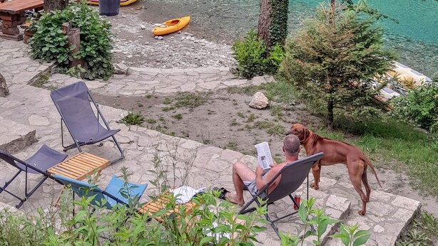 A riverside outdoor area with seating, a dog, and kayaks. - Rafting Camp Encijan (Foca)