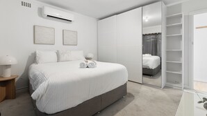 Une chambre moderne avec un grand lit, une armoire et une table de chevet avec une lampe.