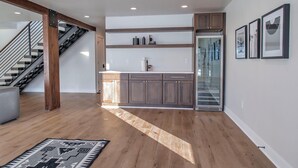 Une cuisine moderne avec des meubles en bois, un four encastré et un réfrigérateur à porte vitrée.