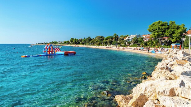 A coastal beach with clear waters, a rocky shoreline, and a small inflatable structure. - Room-cozy Room Near Beach D (Novalja)